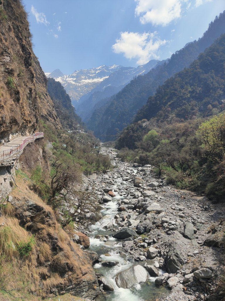 Yamuna river and the Kalini peak range forming a backdrop. 
Well paved path to Yamunotri is visible on the left