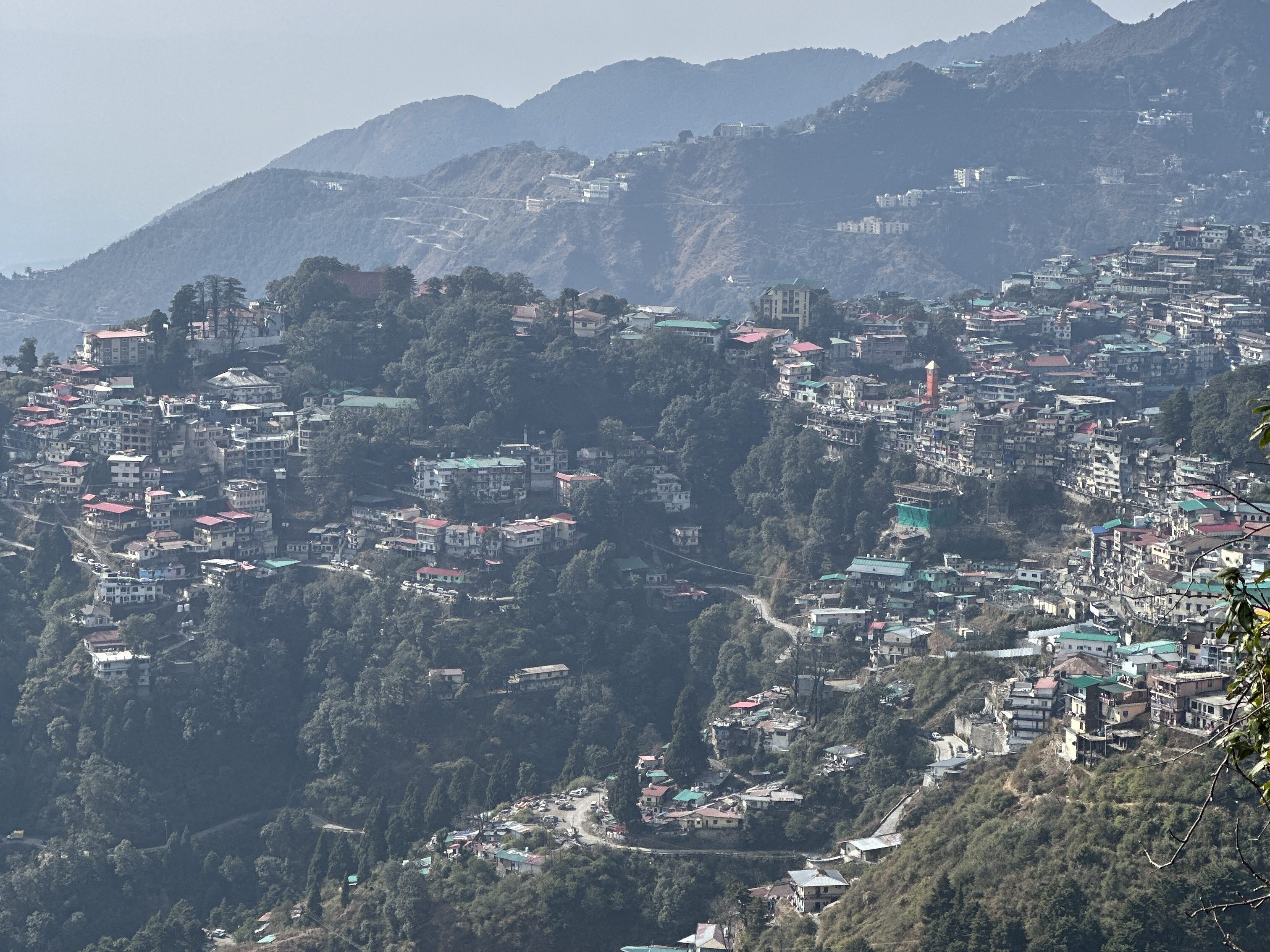 View of the Landour settlement. The Landour clock tower (in orangish hues). Photo clicked from the upper reaches of Landour (near the Sister's Bazar) #Landourdiaries #Mussoorie #Uttarakhand #Landourwalks #mountainview #serene #clearday #sunny #hills #trekking #hiking #shorttrails #walking #mountainwalks