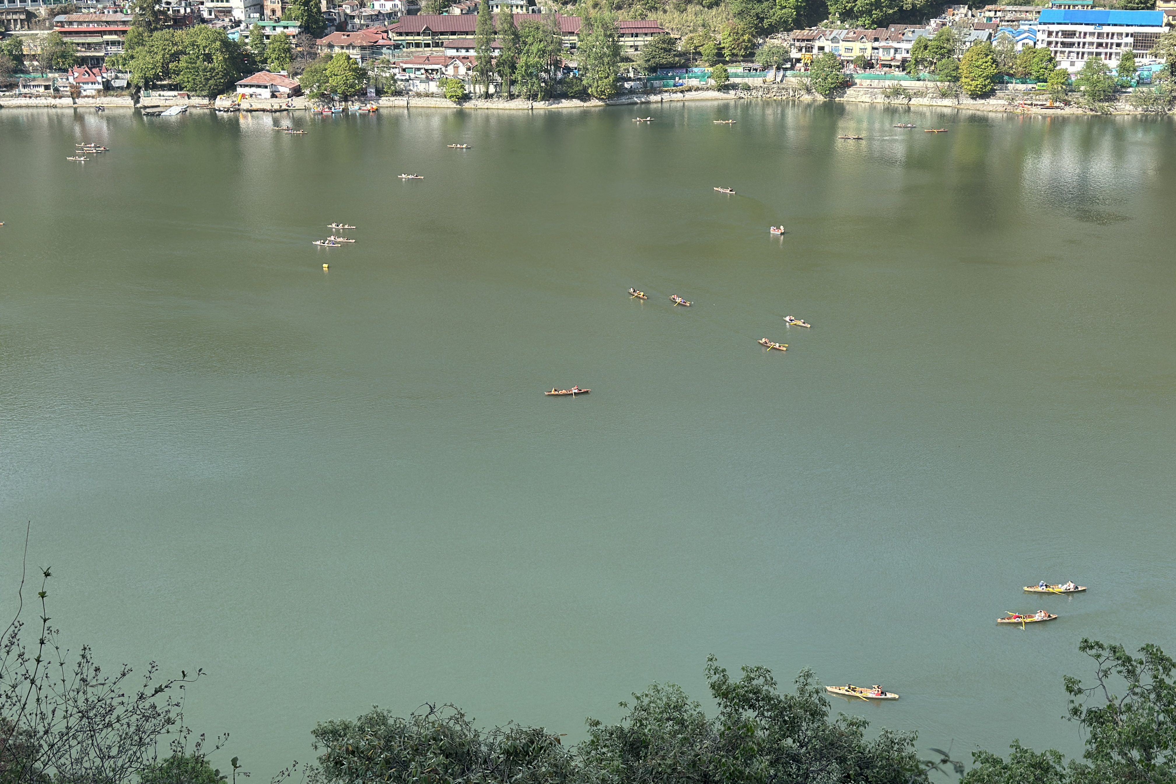 View of Naini Lake from Ayarpatta Hill, shimmering bright and green in the afternoon sun, dotted with a handful of boats drifting gently across its surface.#nainilake #Kumaon #Pahad #Lakeview #SummerinNainital #BoatinginNainital #Mountainview #Himalayanlandscape #DevbhoomiUttarakhand #HillstationsofIndia #IncredibleIndia